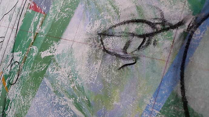 angled photo of a painting detail showing a charcoal drawing of an eye.